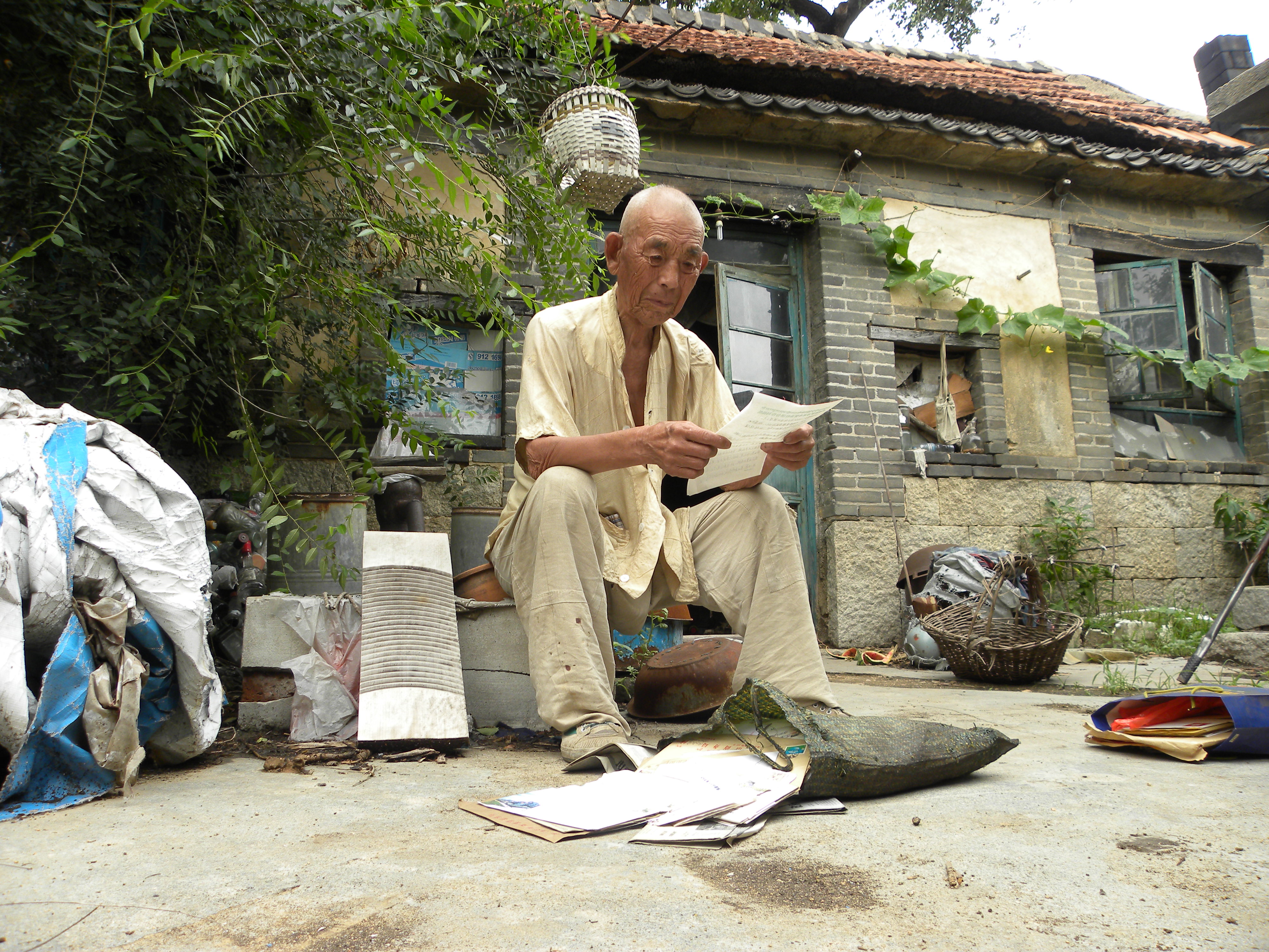 2011年7月25日刘盛兰在自己的小院里仔细阅读他资助的学生们的来信。原晓东 摄 (2).JPG